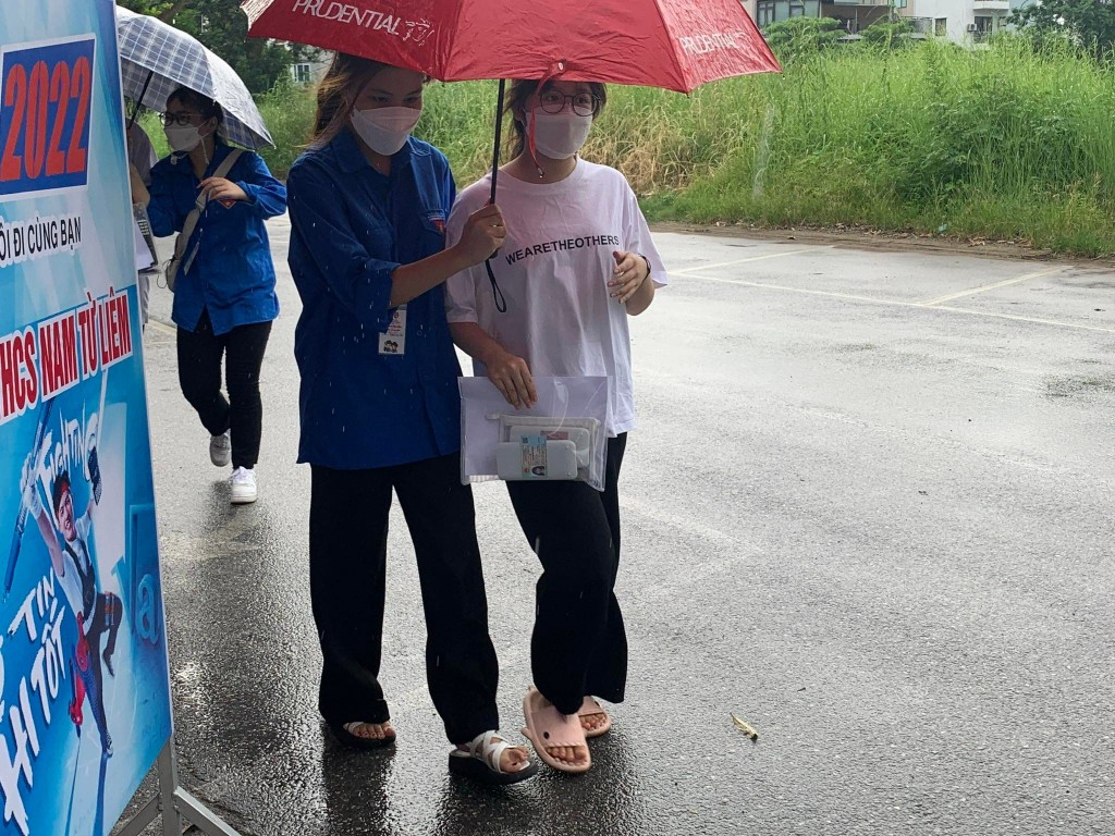 Tình nguyện viên  Thủ đô “đầu trần” hứng mưa, nhường  ô cho các thí sinh