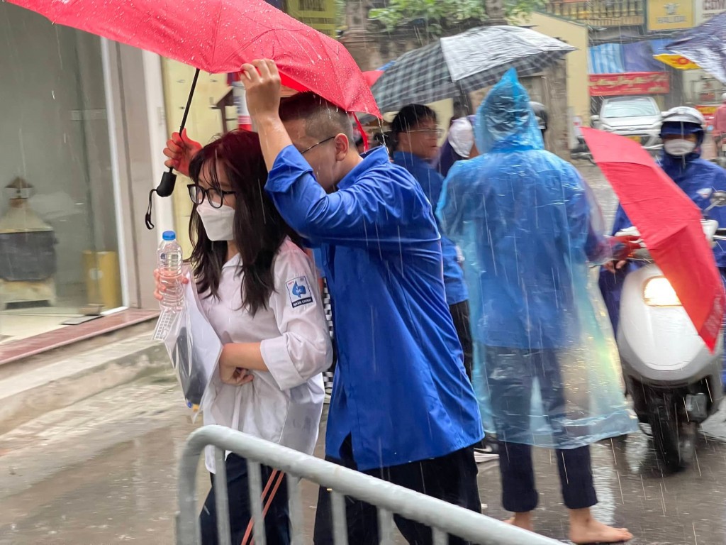 Tình nguyện viên  Thủ đô “đầu trần” hứng mưa, nhường  ô cho các thí sinh