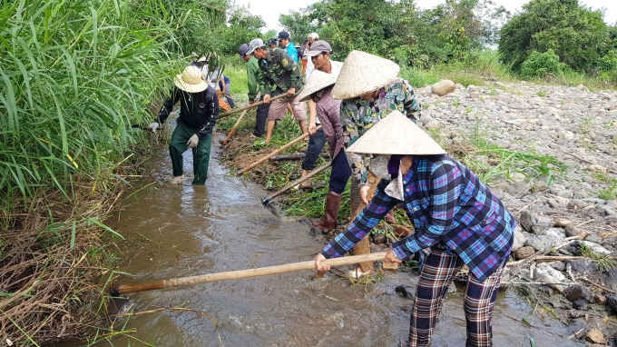 Khơi th&ocirc;ng d&ograve;ng chảy qua những vũng nước dẫn về c&aacute;nh đồng cứu hơn 100ha l&uacute;a đang kh&ocirc; hạn. Ảnh: Mạnh Ho&agrave;i Nam.