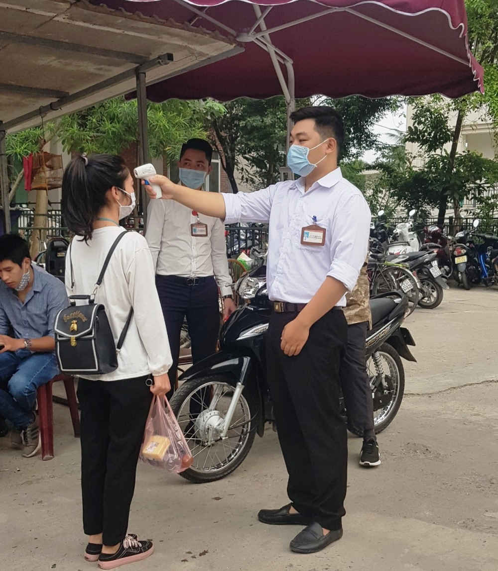 C&aacute;n bộ y tế kiểm tra th&acirc;n nhiệt cho người đến bệnh viện